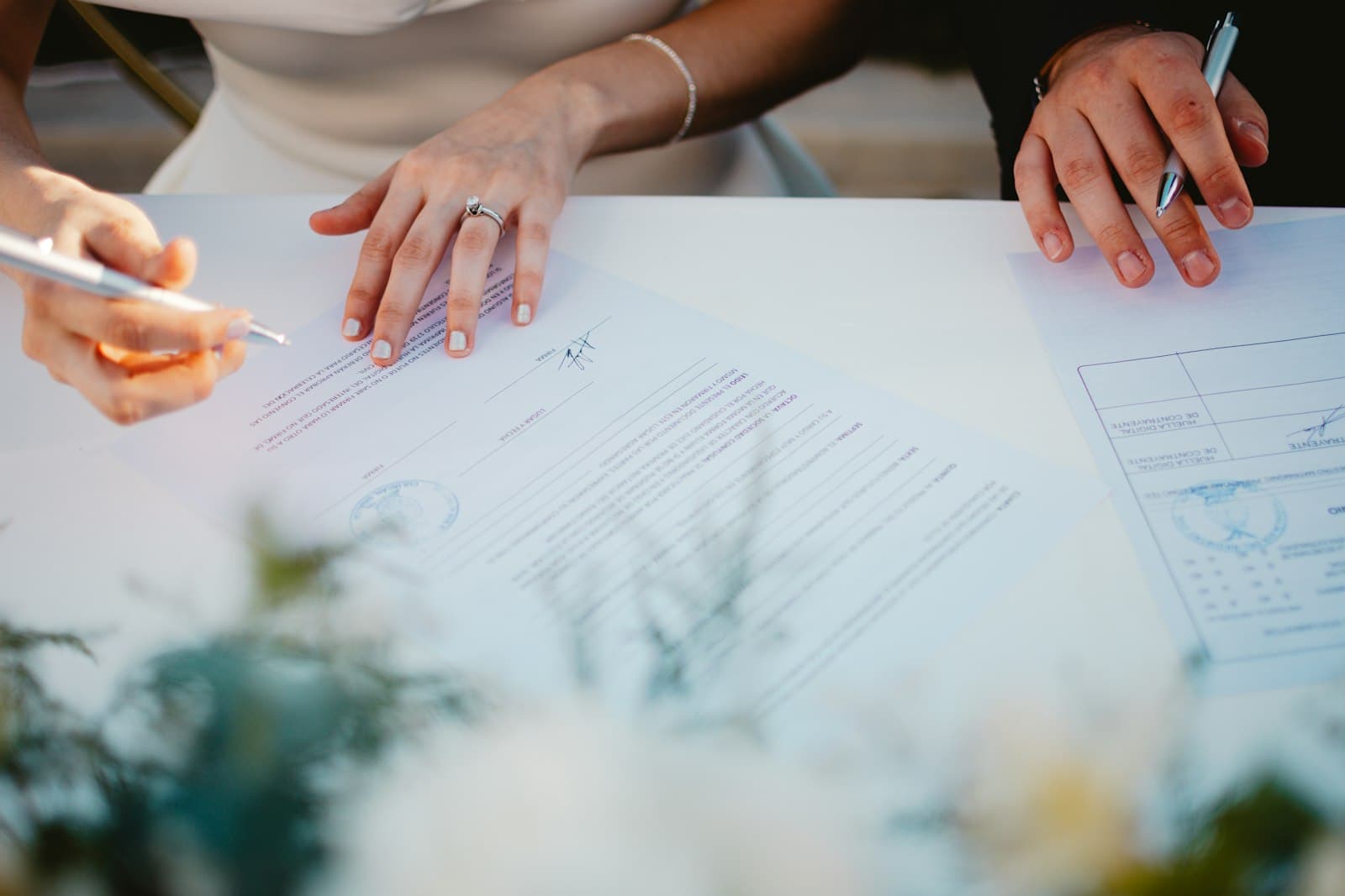 Couple signing marriage documents at a table decorated with flowers