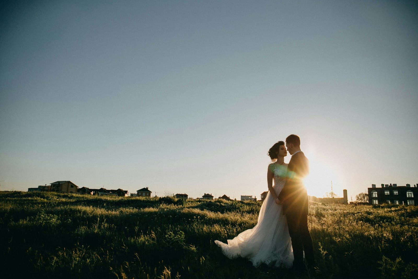 Bride and groom standing in a field at sunset