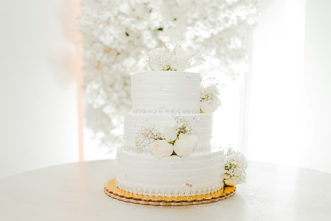 Three-tier white wedding cake decorated with white roses