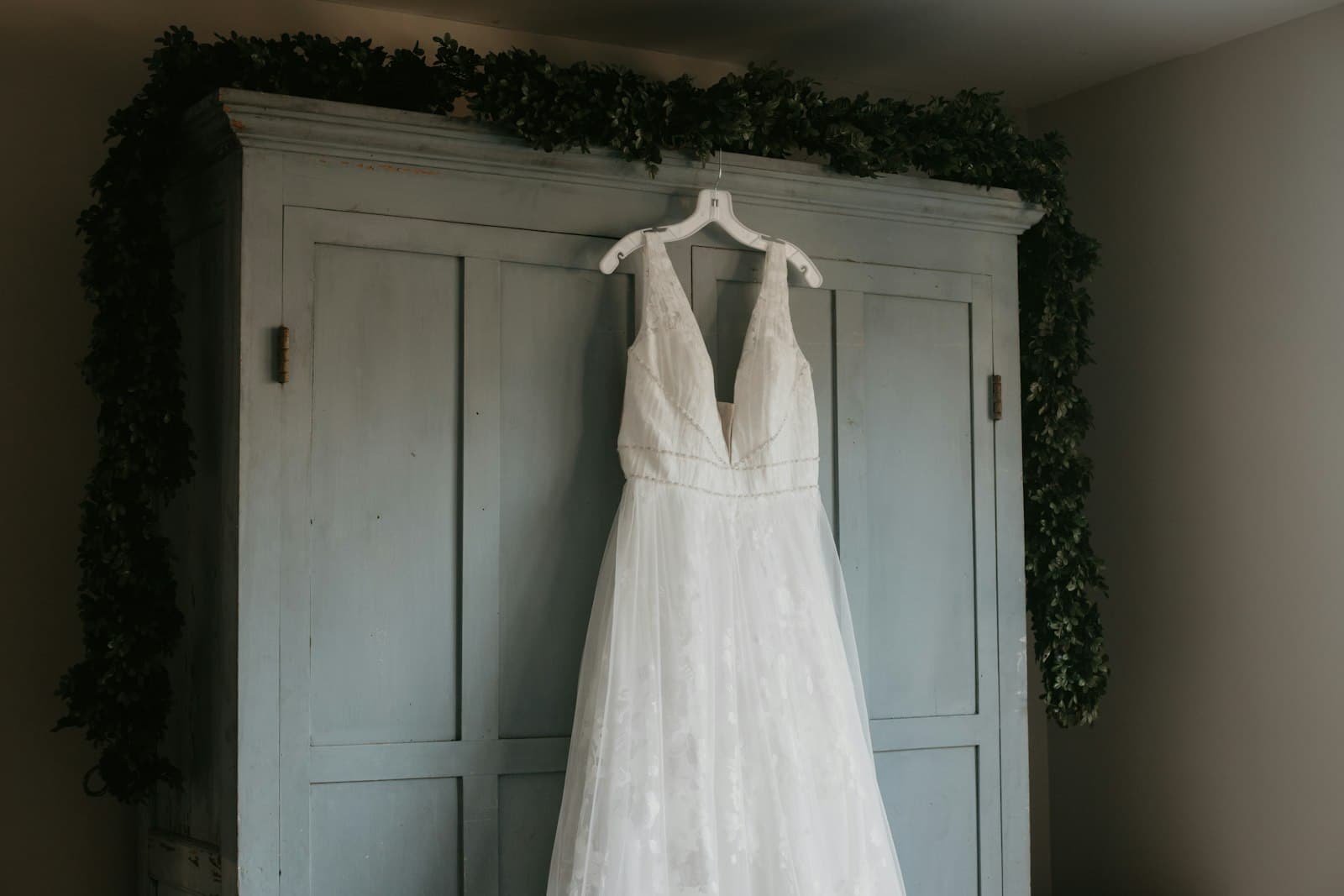 Wedding dress hanging on a wardrobe door trimmed with greenery