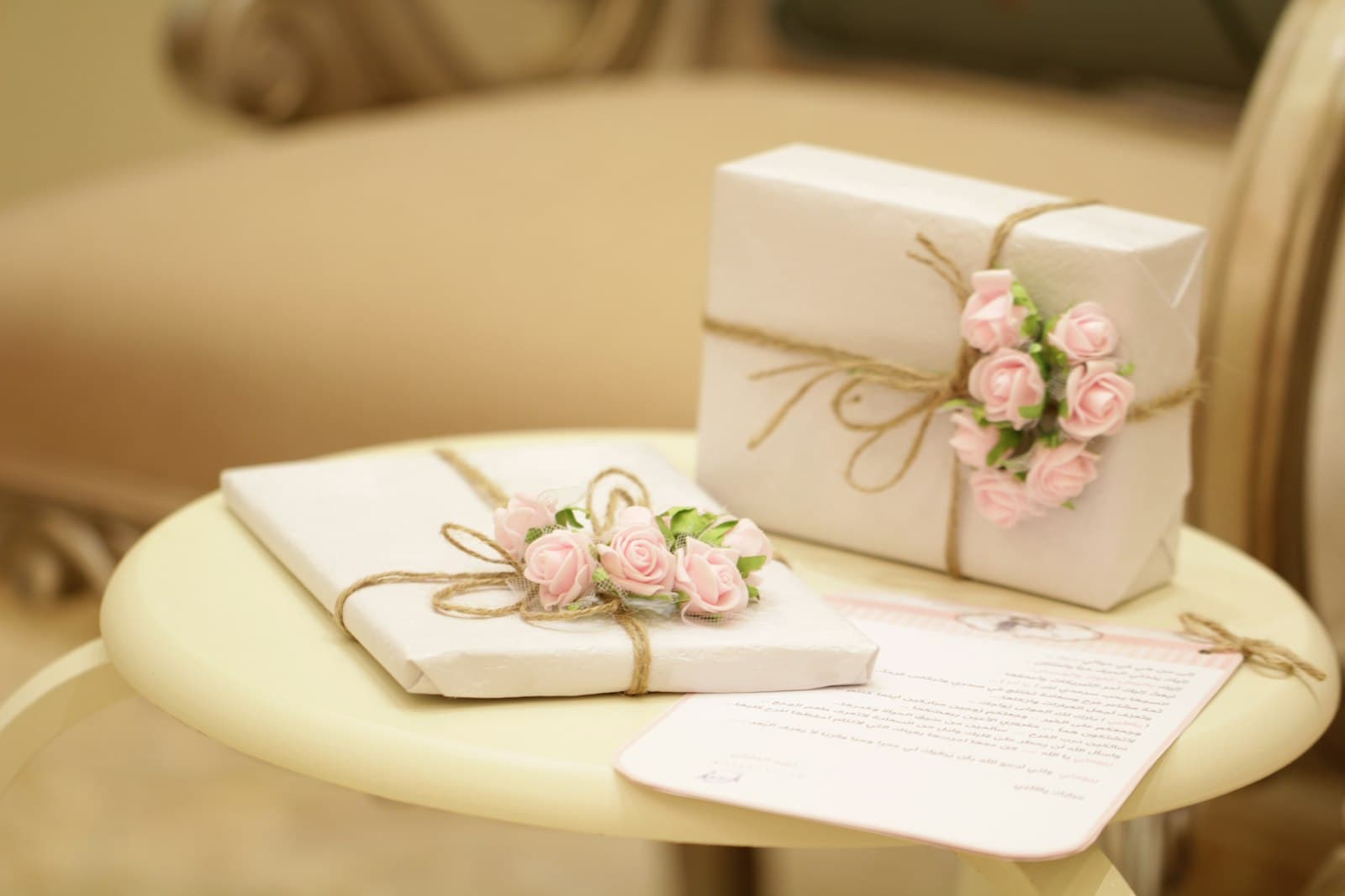 Two wrapped gift boxes decorated with pink flowers on a small table